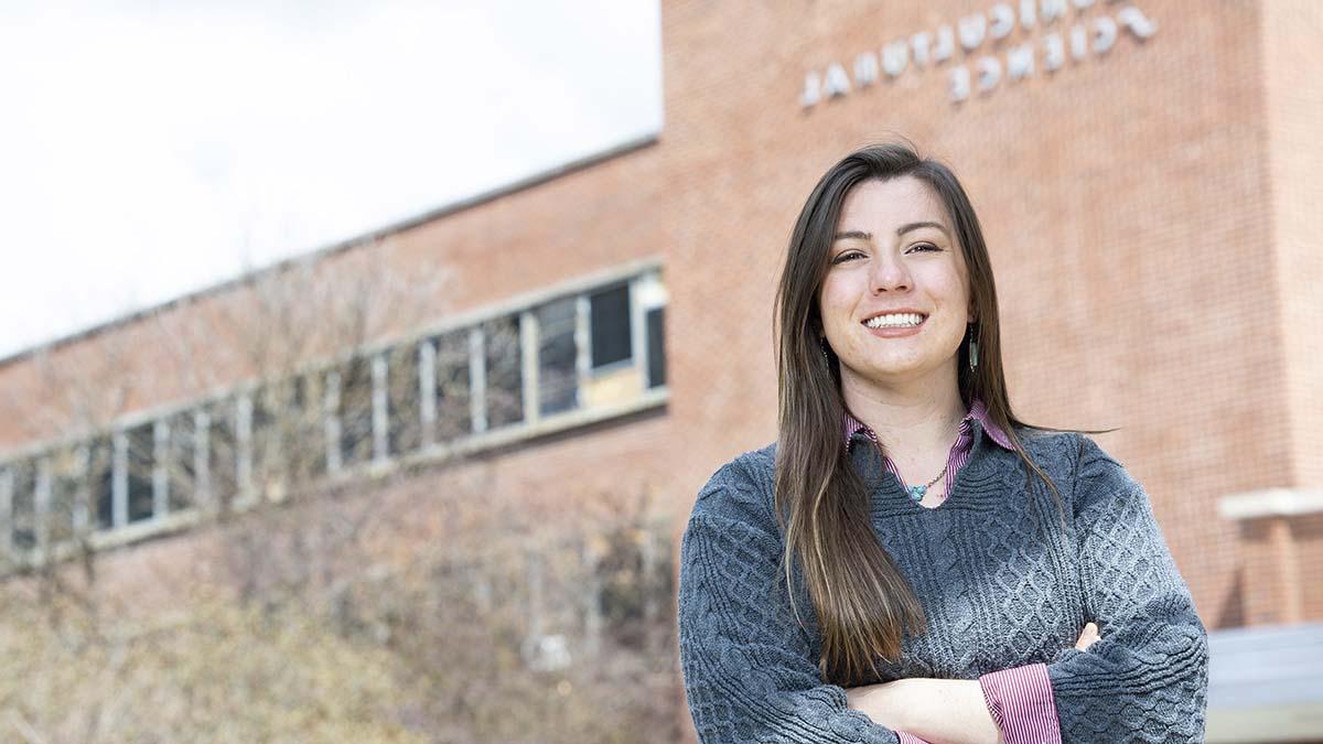 A woman poses outside of a brick building on the bet365亚洲官网 campus.